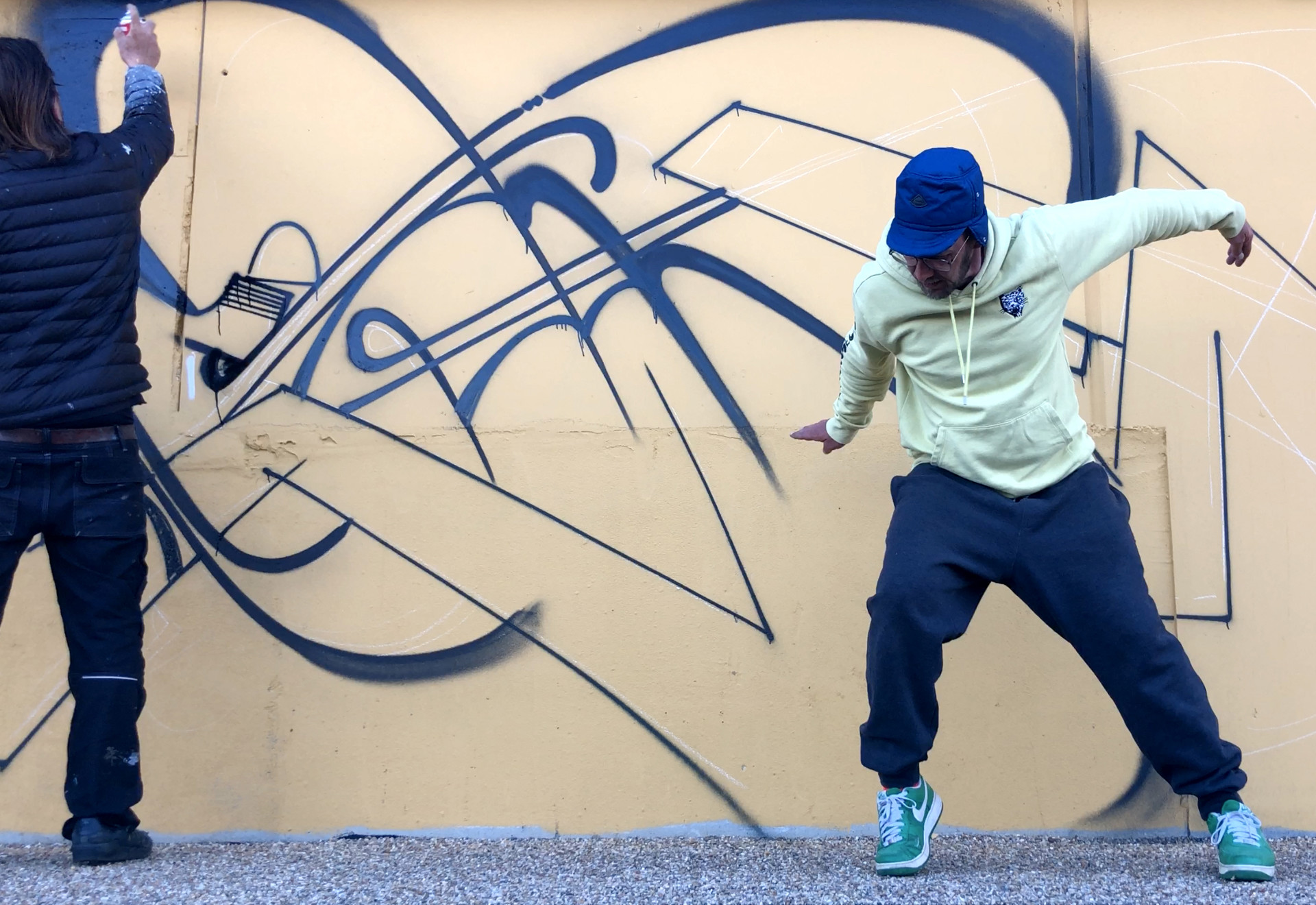 To personer er ved at lave grafitti på mur